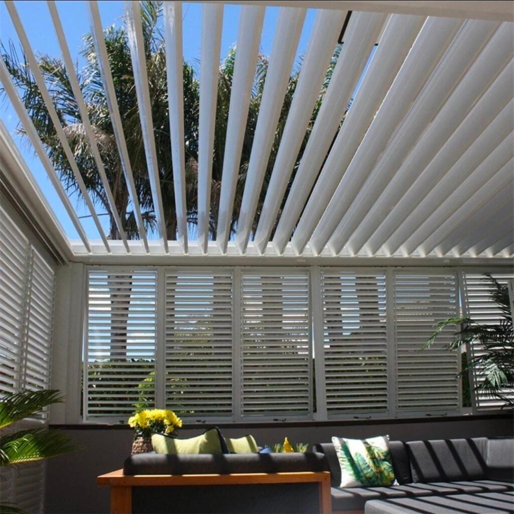 White louvered pergola with adjustable aluminium louvres over an outdoor seating area